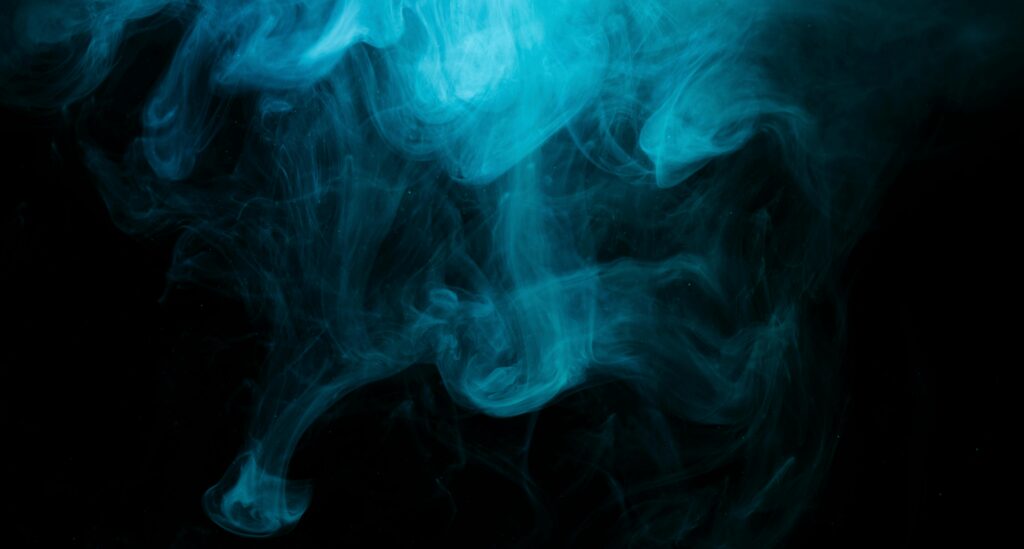 Dynamic blue smoke swirling against a dark background, creating a mysterious and abstract effect.