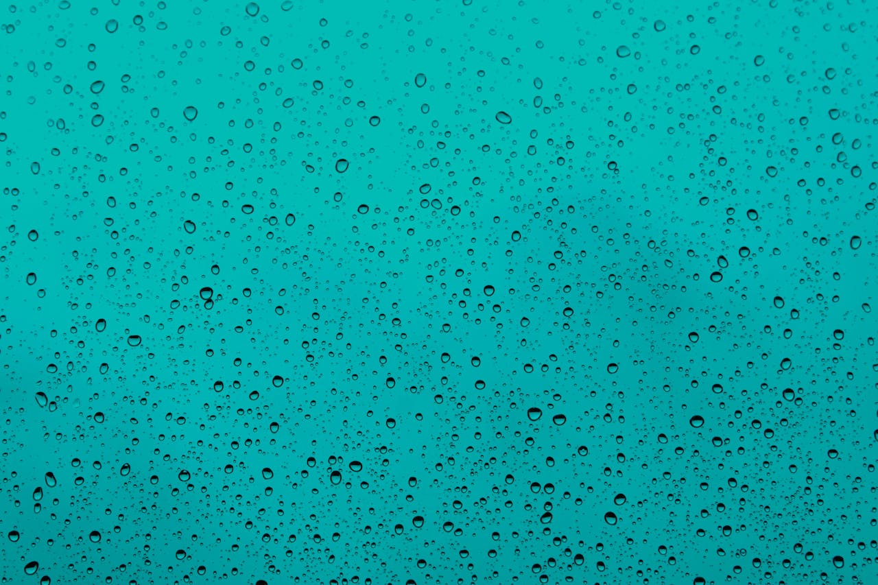 Crafting Captivating Headlines: Your awesome post title goes here Close-up of water droplets on a teal glass window, capturing the beauty of rain.
